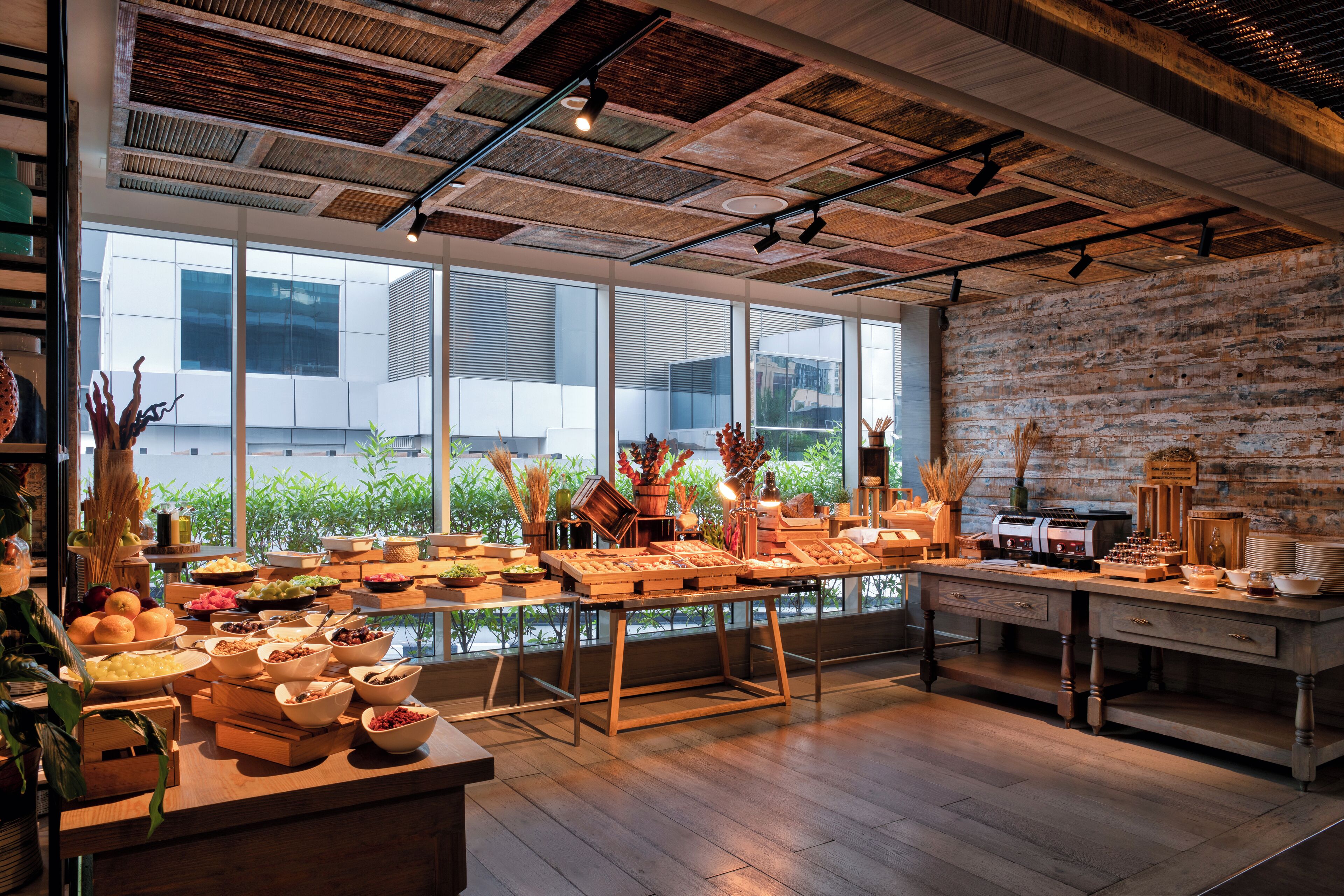 A breakfast buffet with various food items and a rustic brick wall.