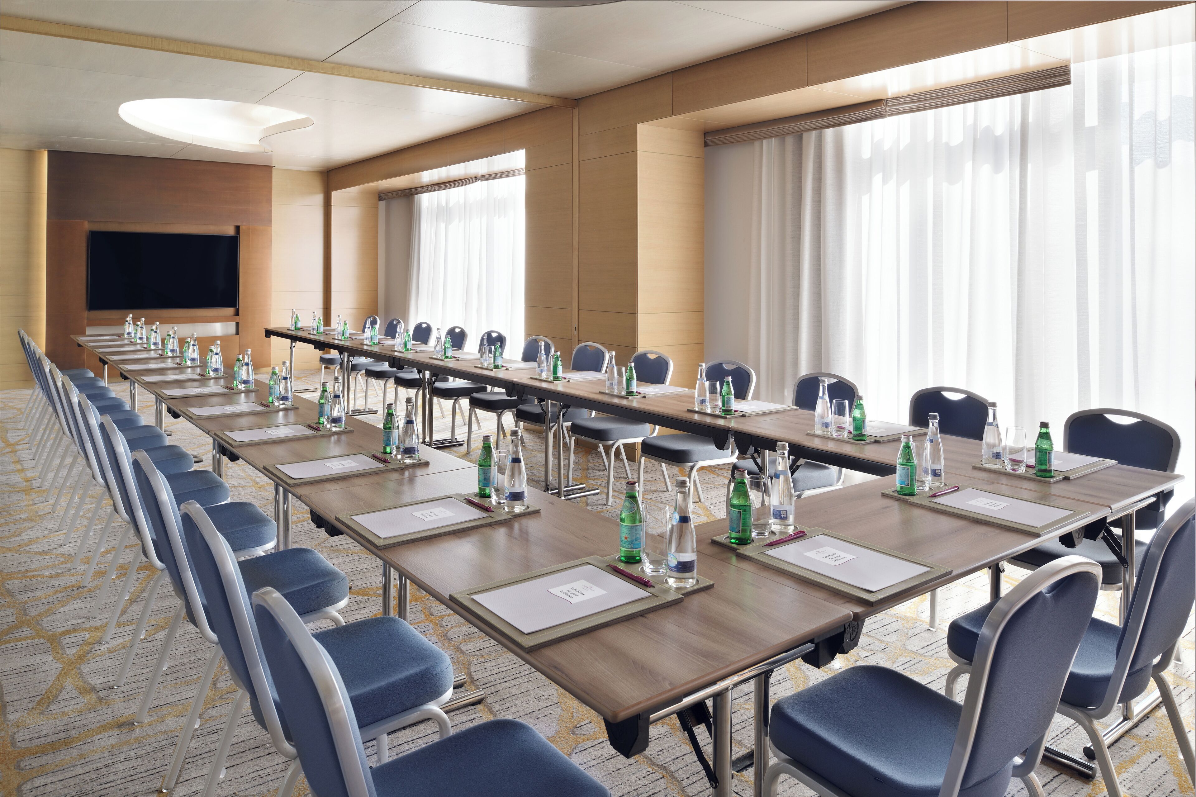 A conference room with long tables, chairs, water bottles, and nameplates.
