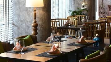 A restaurant interior with wooden tables, chairs, and a 'Welcome To Charm Thai' sign.