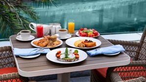 Une table à manger avec des aliments pour le petit-déjeuner et une vue sur la piscine.