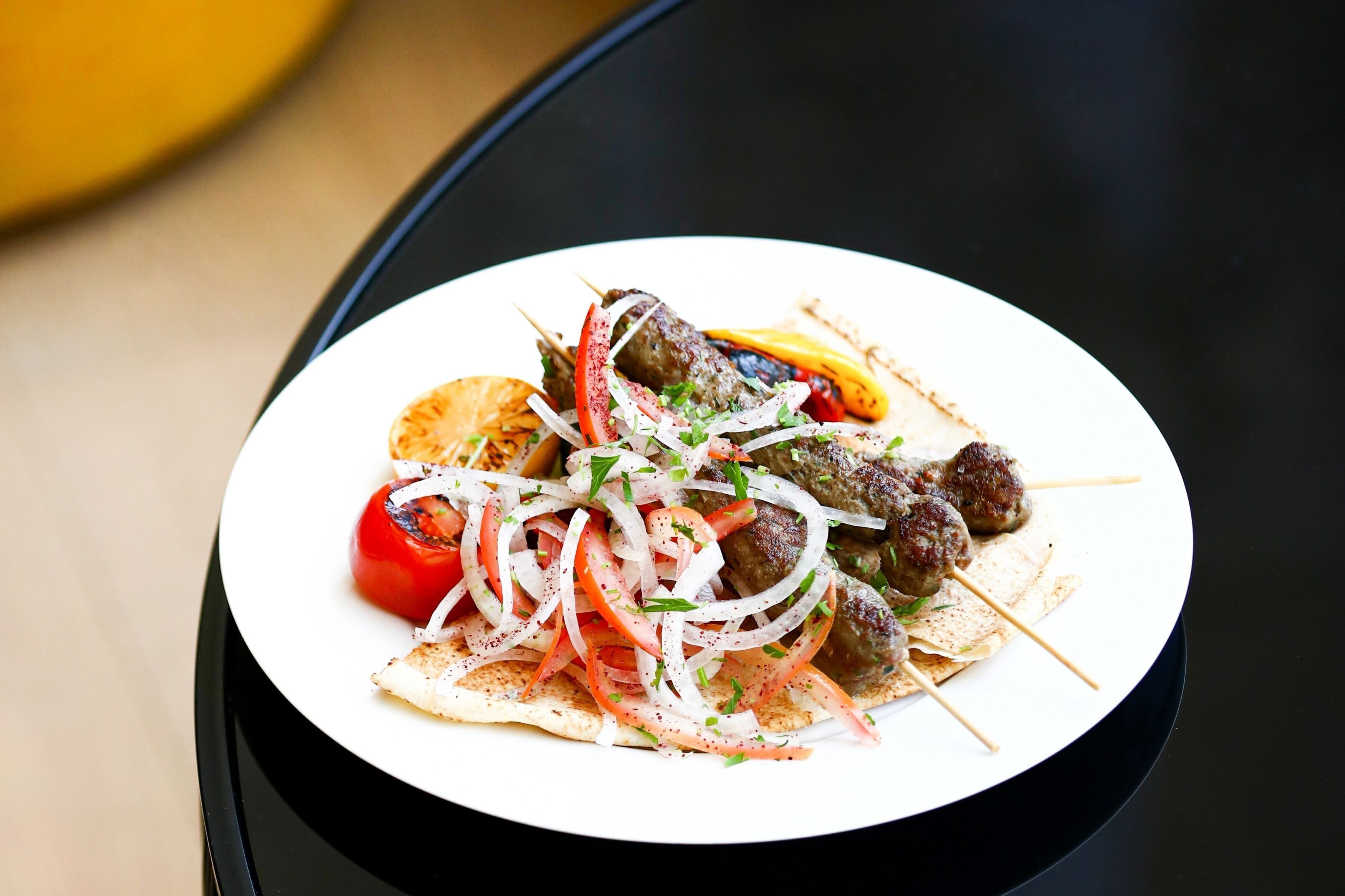 A plate of kebabs with vegetables and flatbread.
