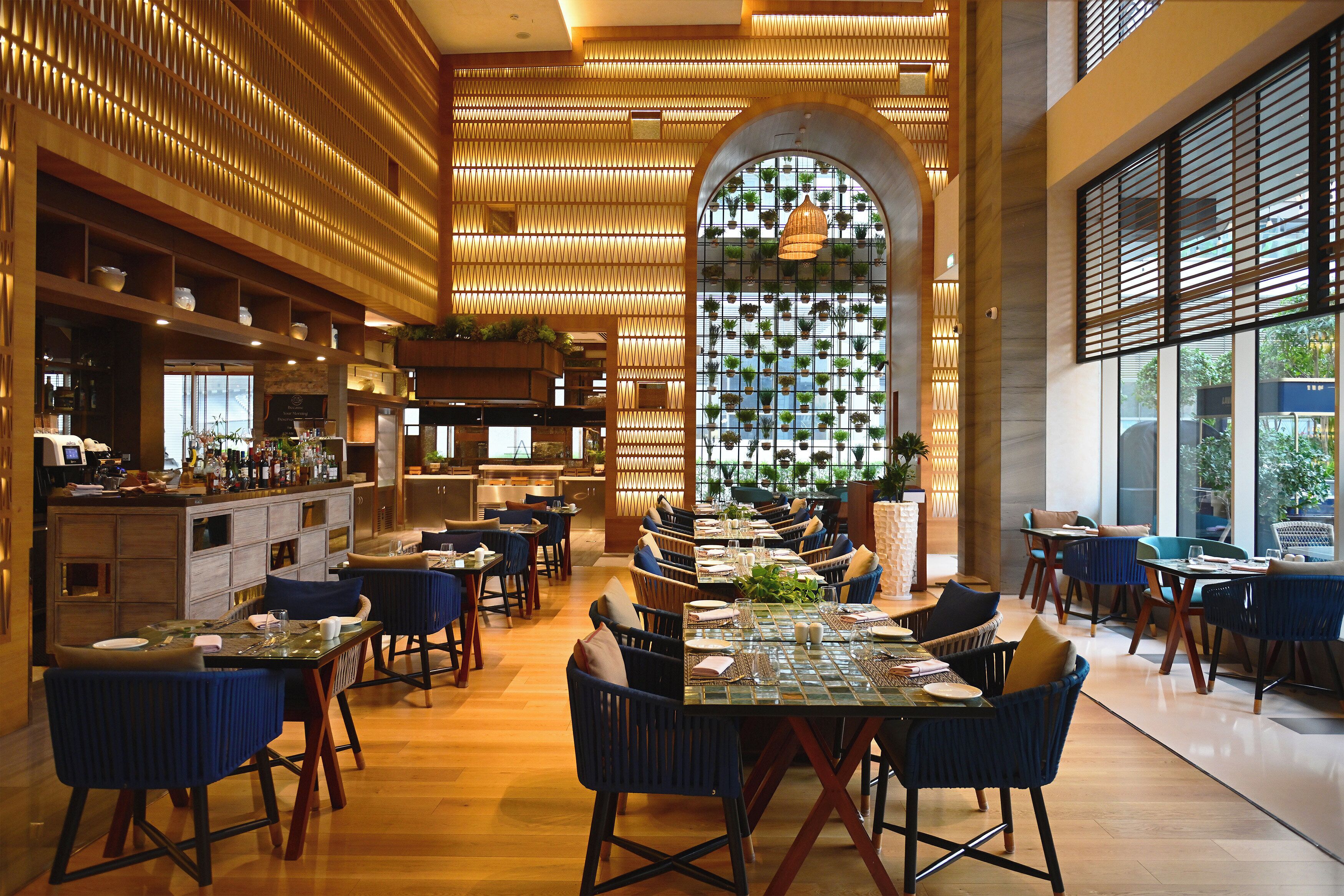 A spacious restaurant with high ceilings, wooden paneling, and a central dining area with tables and chairs.