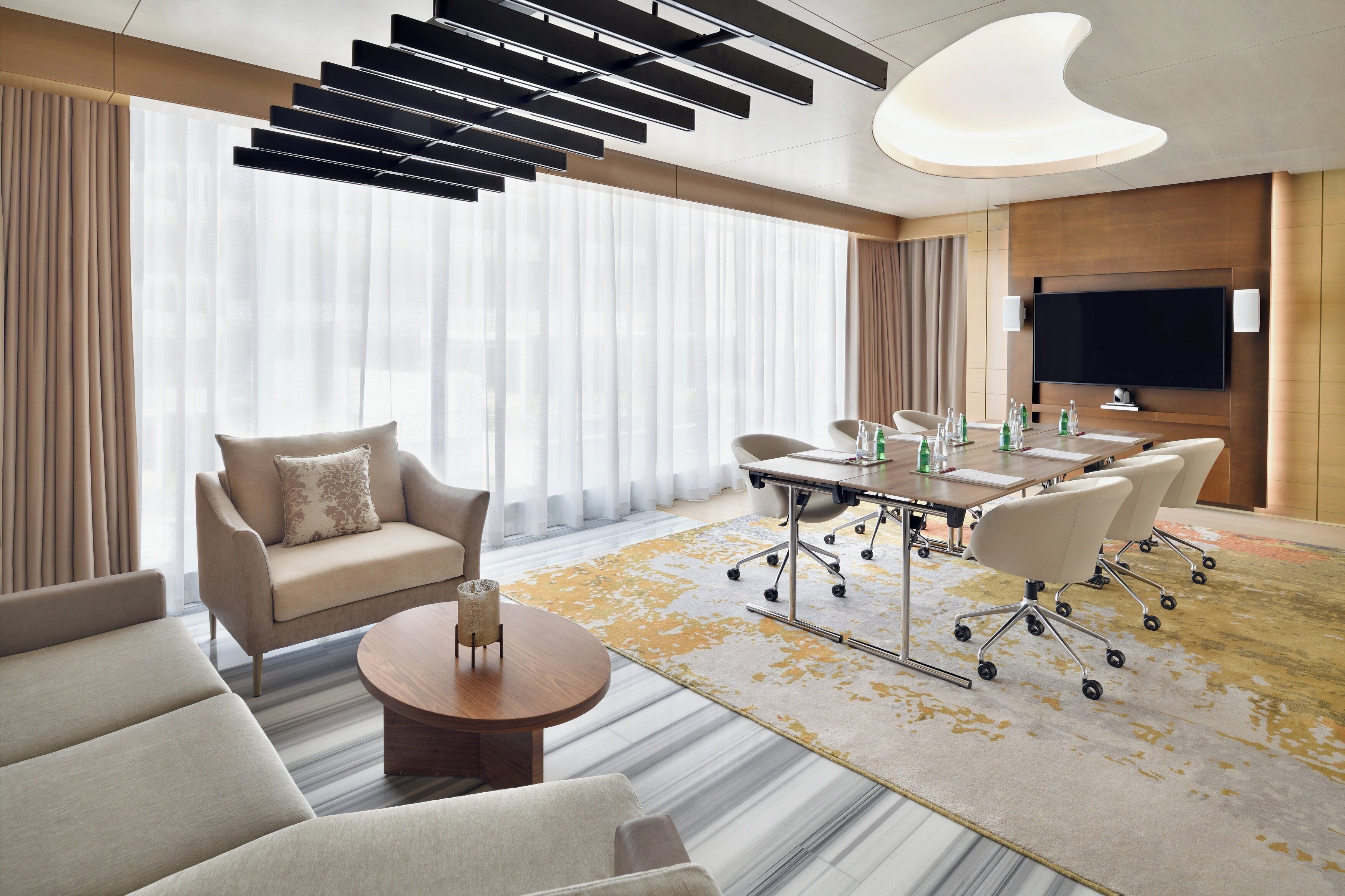 A modern conference room with a large table, chairs, and a television.