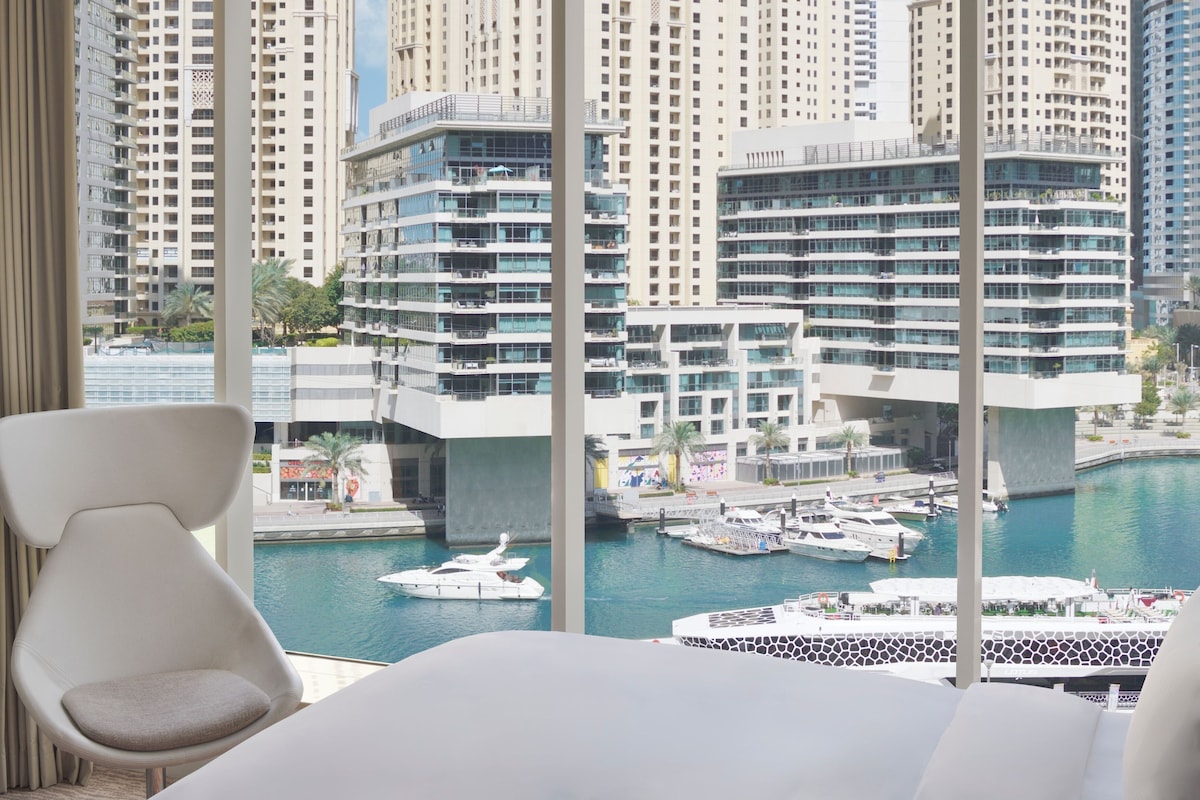 A hotel room with a view of a marina and high-rise buildings.