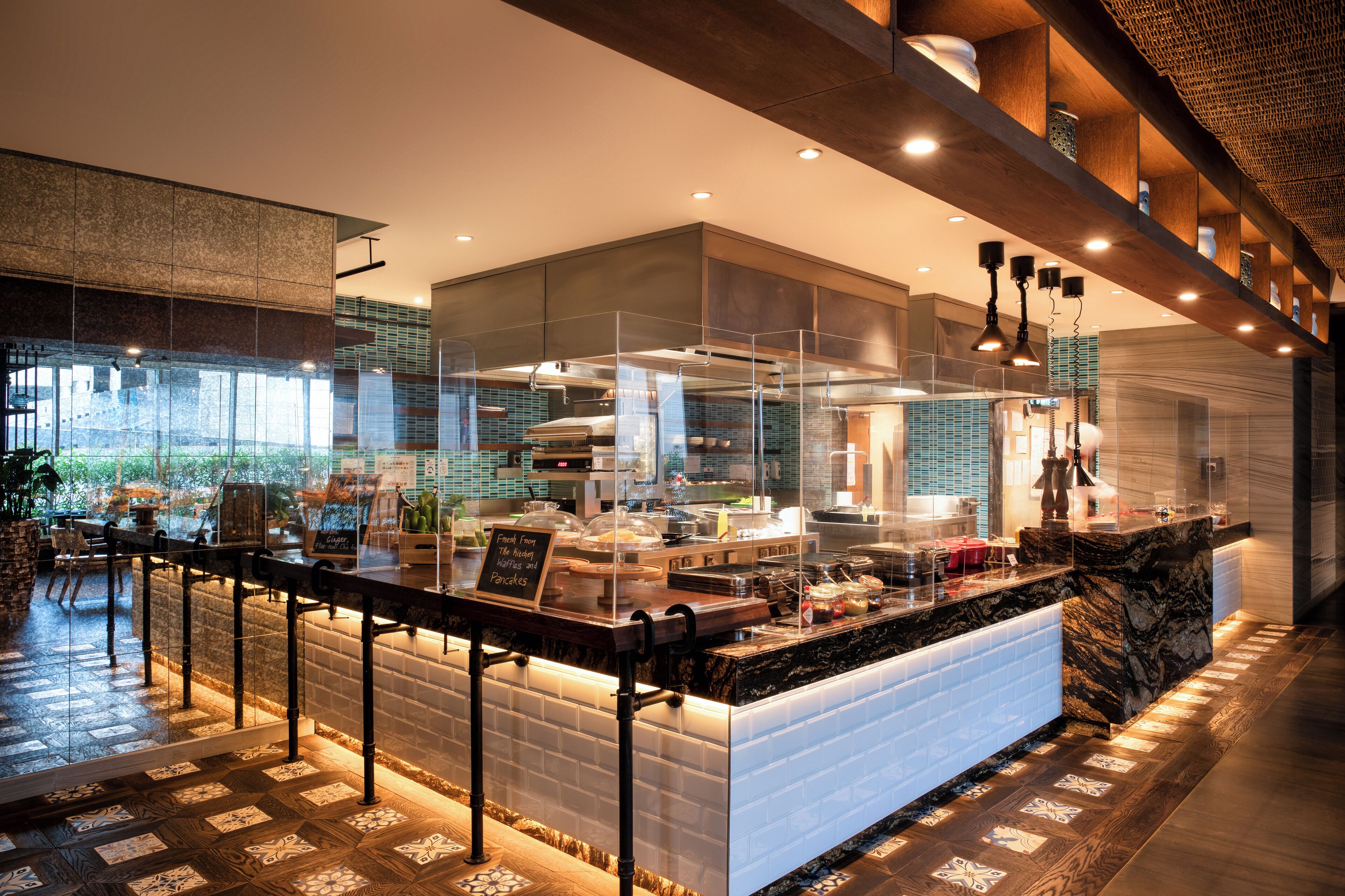 A modern kitchen with a marble countertop, glass enclosure, and a sign indicating breakfast options.