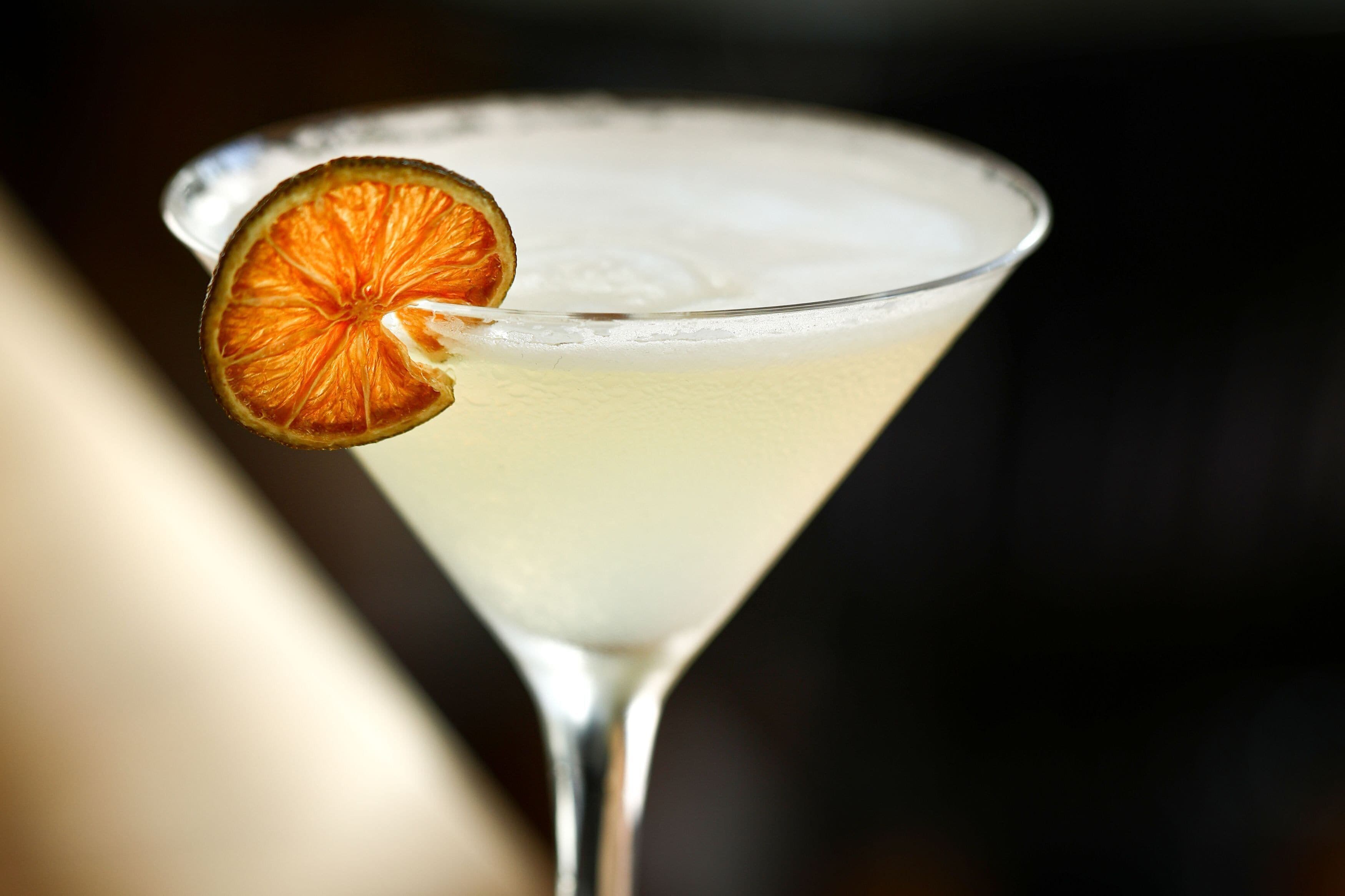 Un verre à martini contenant un liquide clair et garni d’une tranche d’orange séchée.