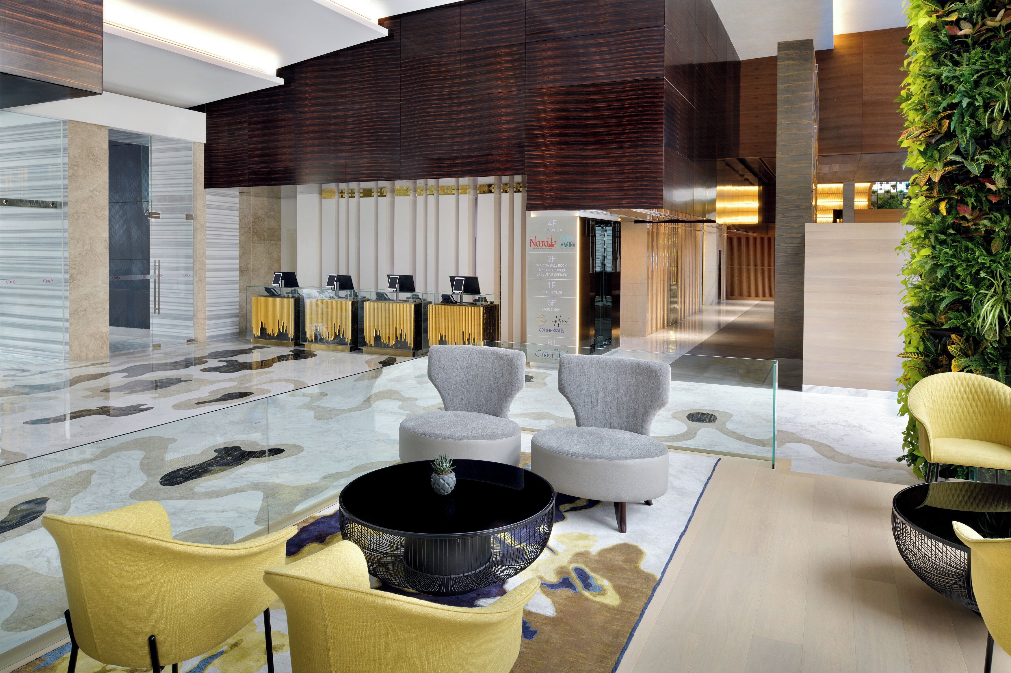 Eine moderne Lobby mit Sitzgelegenheiten, einer Rezeption und einer vertikalen Begrünung.