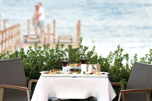Une table dressée avec de la nourriture et des boissons, donnant sur une étendue d’eau.