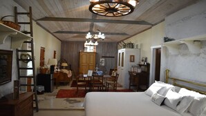 Una habitación con cama, escritorio, silla, mesa de comedor y candelabro.