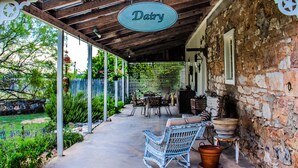 Un patio cubierto con muebles de mimbre, una pared de piedra y un letrero que dice "Dairy".