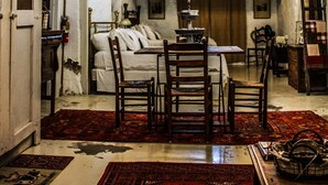 Un interior rústico con techo de madera, una araña, una mesa de comedor con sillas y una escalera.