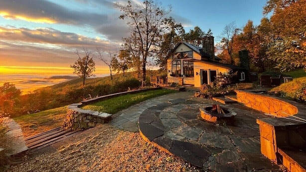 Ein Haus mit einer Steinterrasse, einer Feuerstelle und Blick auf die umliegende Landschaft.