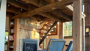 Ein rustikales Interieur mit freiliegenden Holzbalken, einem Steinkamin und zwei blauen Sesseln.