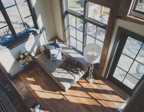 Relax in a serene space with a comfortable seating area, large windows offering views of the outdoors and a cozy bench.