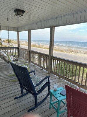 A wooden porch with a rocking chair, a small table, and a view of the beach. - OCEANFRONT! Fall dates still available (Folly Beach)
