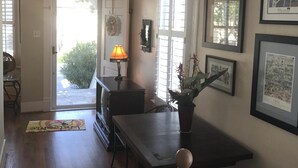 A spacious living area with a wooden floor, a dining table, and a staircase with a wooden railing.