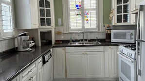 A kitchen with white cabinets, a black and white tiled floor, a stove, a microwave, and a chandelier.
