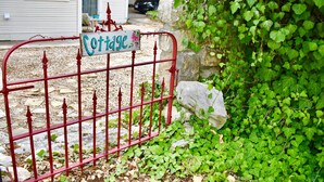 A gated entrance with a sign reading "Cottage." - Romantic Ava Haus Cottage. 3 minutes to Main! See our other 4 Ava Haus rentals. (Fredericksburg)