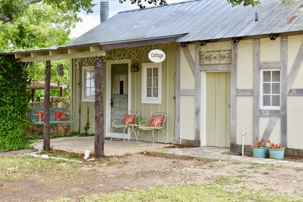 Ein rustikales Gebäude mit einer Veranda, zwei Stühlen und einem Schild mit der Aufschrift 'Cottage'.