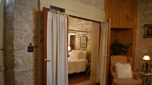 A room with a bed, a chair, and a small table with a lamp.