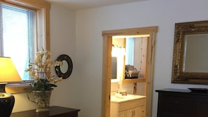 A bedroom with a bed, dresser, and a mirror. There is a window with blinds, a lamp, and a potted plant. - Girdwood Alaska rental near ski resort. Customers rave: so cute, clean and cozy! (Anchorage)