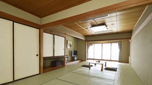 A traditional Japanese room with tatami flooring, sliding doors, a low table, and a television. - Hotel Suimeikan (Yamanouchi)