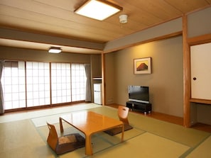 A traditional Japanese-style room with tatami flooring, a low table, a television, and sliding doors. - Hotel Suimeikan (Yamanouchi)