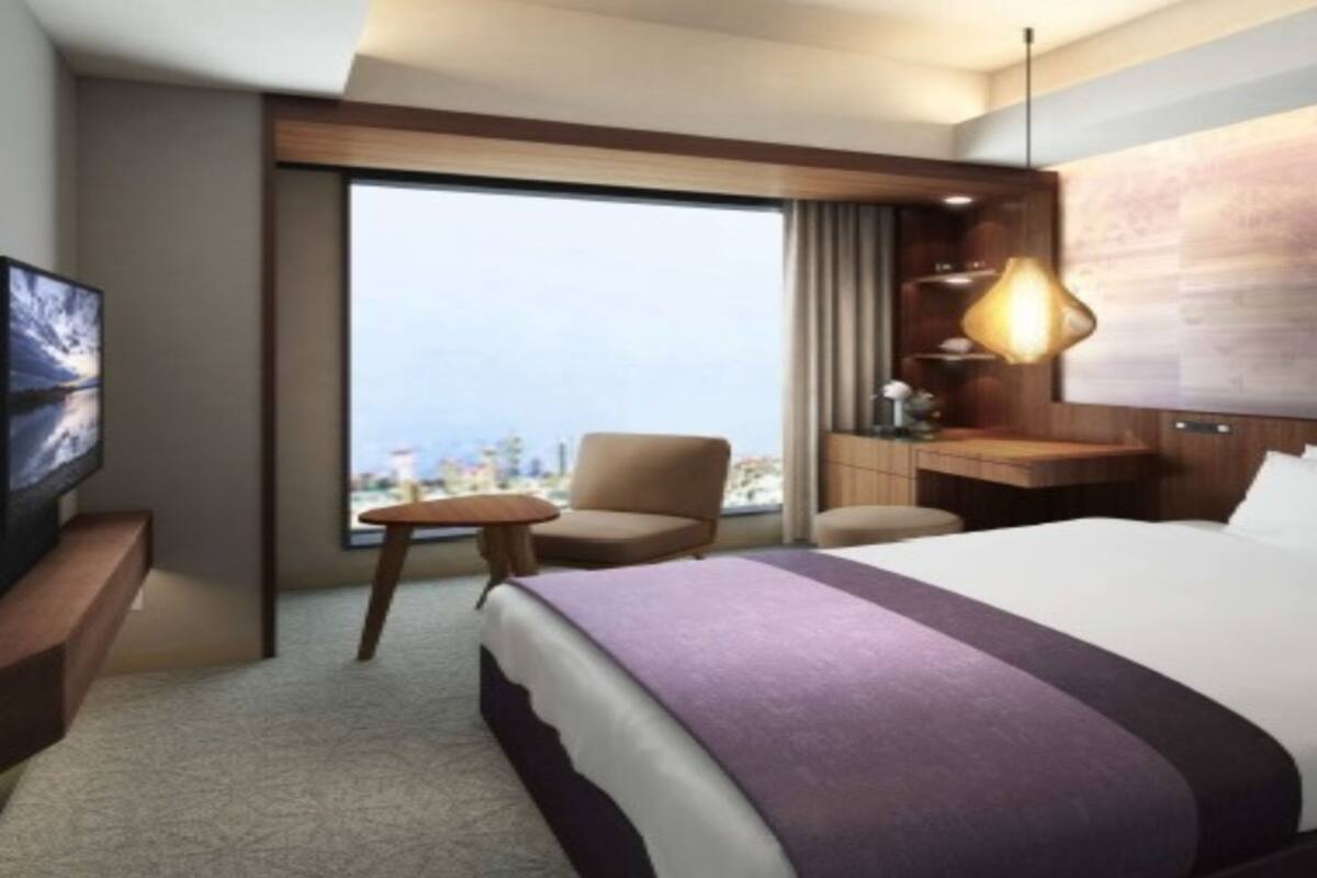 Une chambre d’hôtel avec un grand lit, un bureau, une chaise, une télévision et une vue sur la ville.