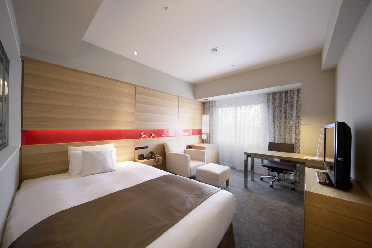 Une chambre d’hôtel avec un grand lit, un bureau, une chaise et un téléviseur.
