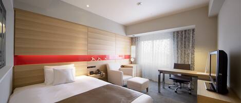 A hotel room with a large bed, a desk, a chair, and a television.