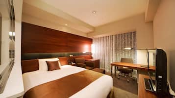 A hotel room with a large bed, a desk, a chair, a TV, and a mirror.