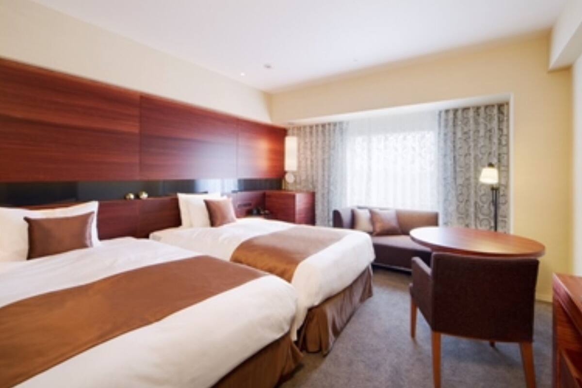 Une chambre d’hôtel avec deux lits, un coin salon et une petite table.