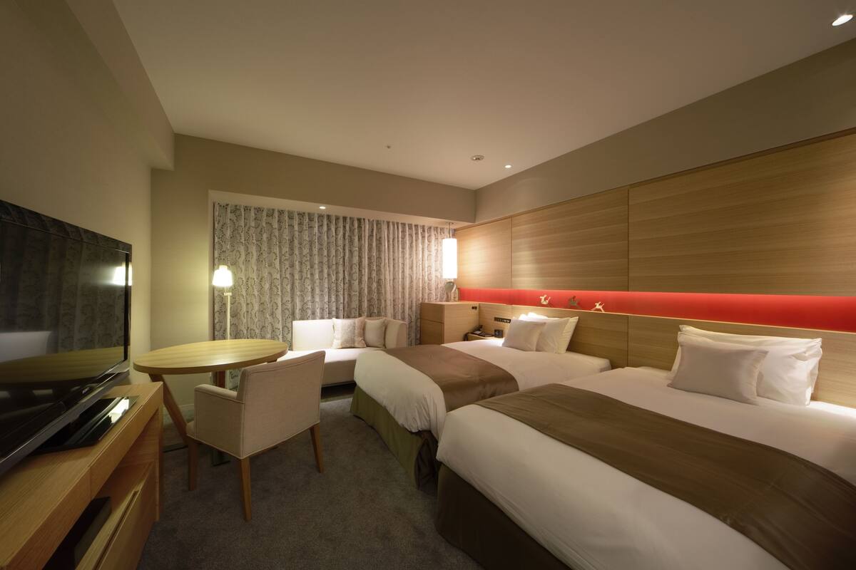 Une chambre d’hôtel avec deux lits, une télévision, un bureau et une chaise.