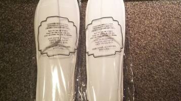 To hvide slippers i plastikemballage med instruktioner på japansk.