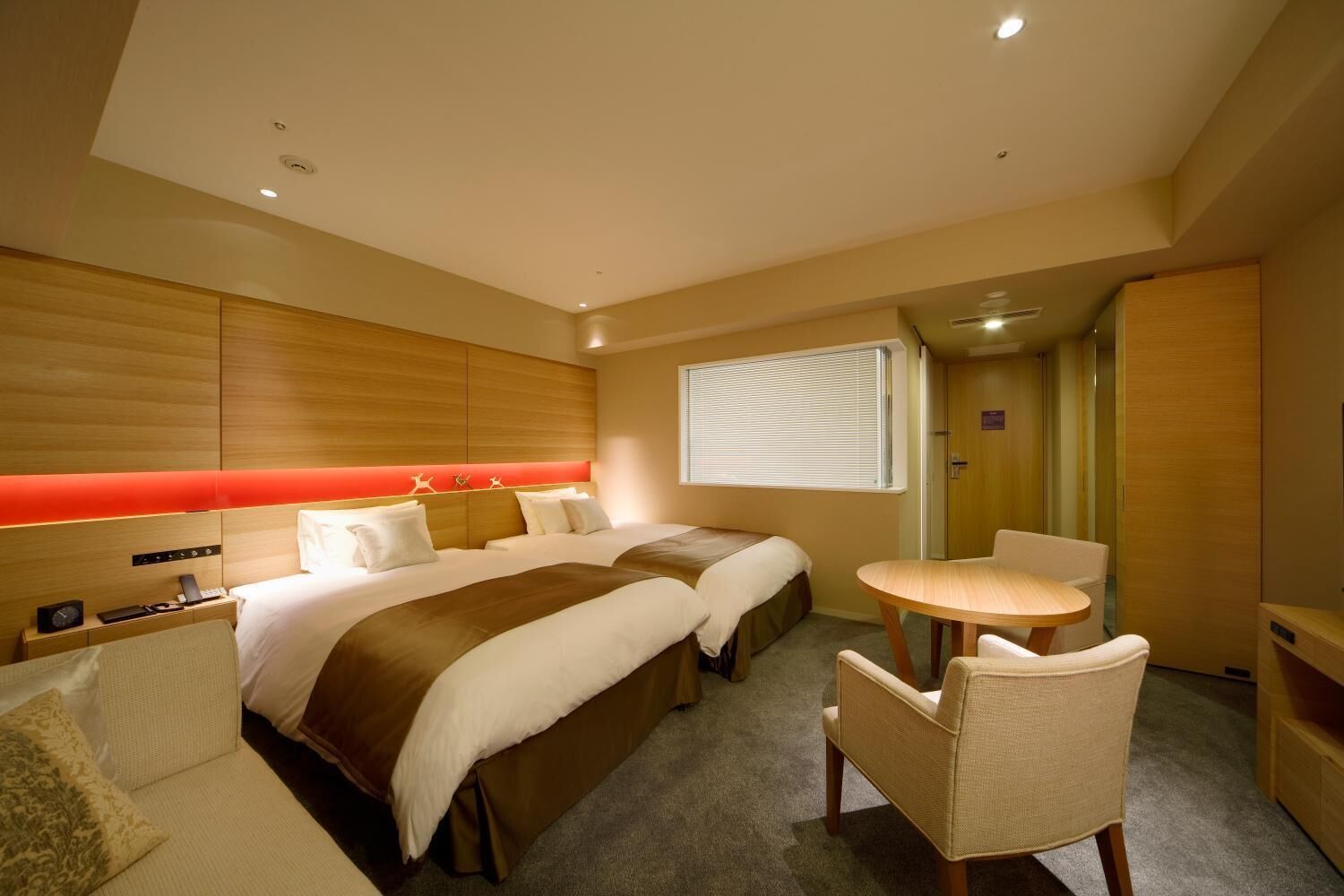 A hotel room with two beds, a small round table, and a chair.