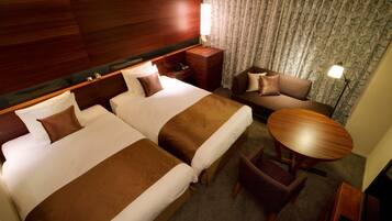 Habitación de hotel con dos camas, un sofá, una mesita y una lámpara.