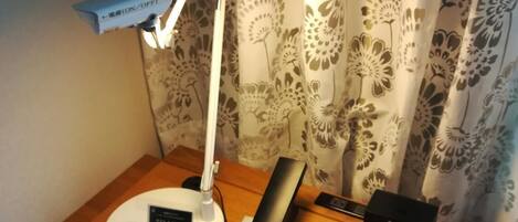 A desk with a desk lamp, a telephone, a clock, and a notepad.