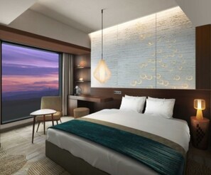 A modern hotel room with a large bed, a view of the sunset, a desk, and a hanging light fixture. - Hotel Metropolitan Akita (Akita)