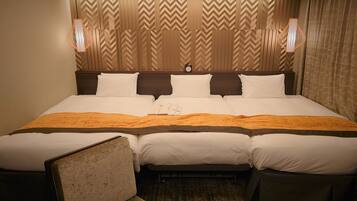 A hotel room with a large bed, two bedside tables, a chair, and a headboard with a chevron pattern.
