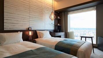 A hotel room with two beds, a large window with a city view, a wall with a textured pattern, and a hanging lamp.
