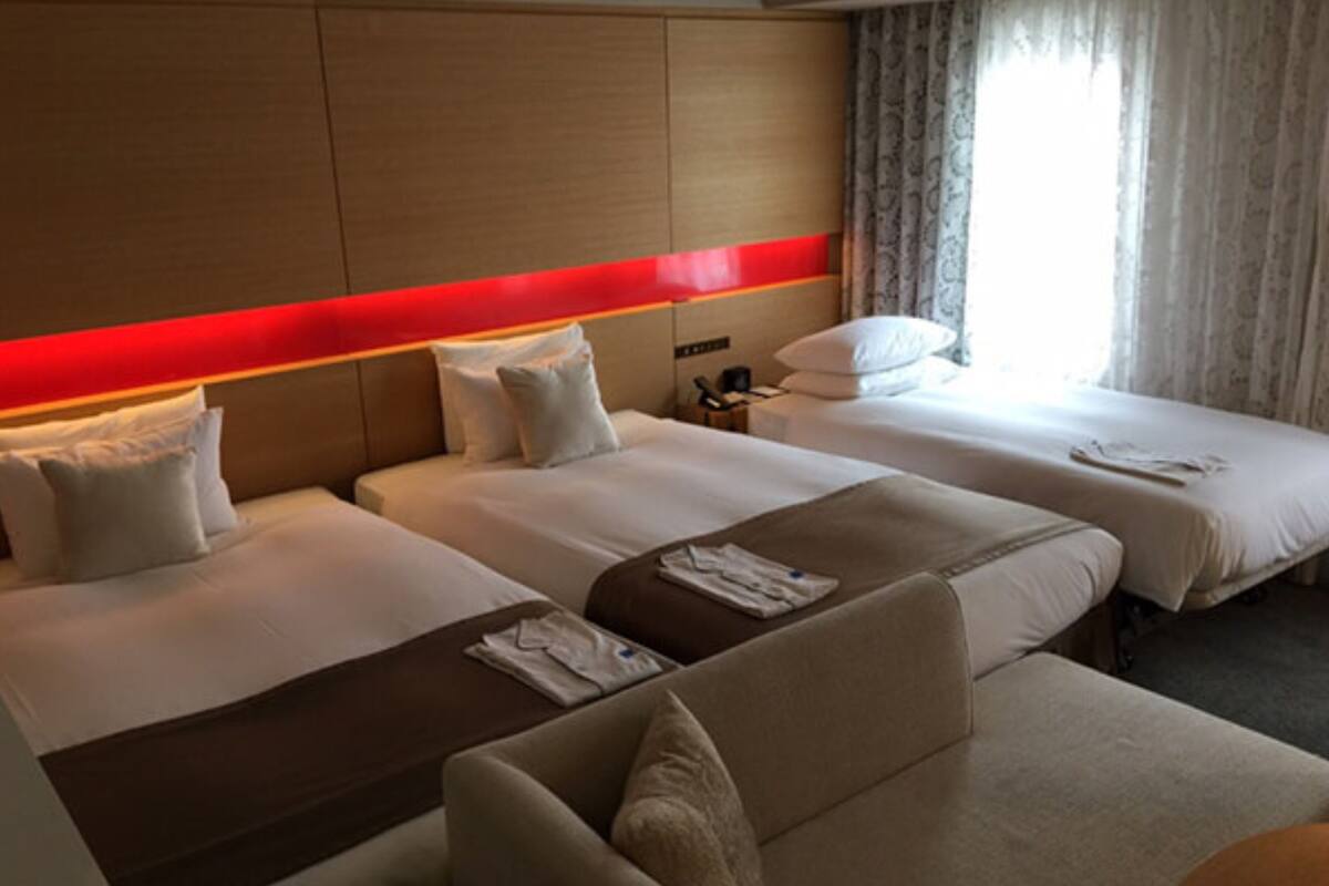 Une chambre d’hôtel avec deux lits, un canapé et une table de chevet.