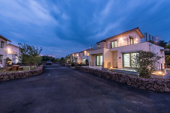 A modern residential street with two-story houses, stone walls, and a paved road. - Dream in Jeju (Seogwipo)