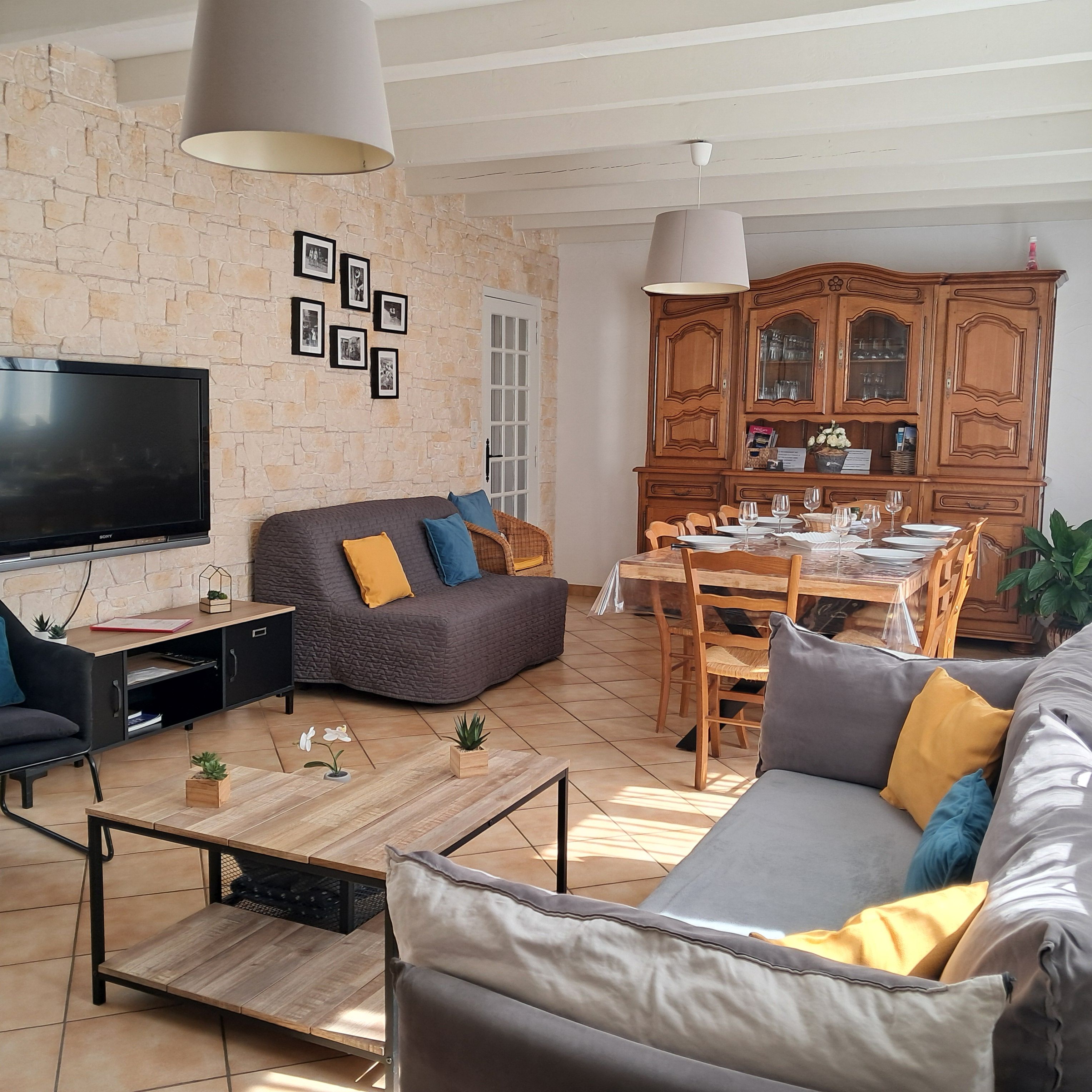 A living room with a sofa, a coffee table, a TV, and a dining area with a table and chairs.
