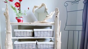 Een witte houten plankenwand met drie lades, een rode pot met rode bloemen, en een lijntekening van een persoon rechts.