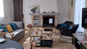 Een woonkamer met een open haard, bank, salontafel en televisie.