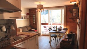 A cozy kitchen with wooden cabinets, a dining table, and a large window offering a view of the outdoors. - The Corbier top comfort! (Villarembert)