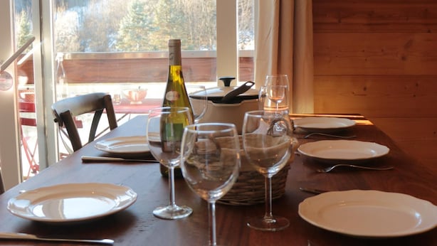A dining table set with plates, wine glasses, and cutlery, with a bottle of wine and a basket of bread. - The Corbier top comfort! (Villarembert)