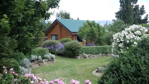 A house surrounded by a well-maintained garden with various flowering plants and a lawn.