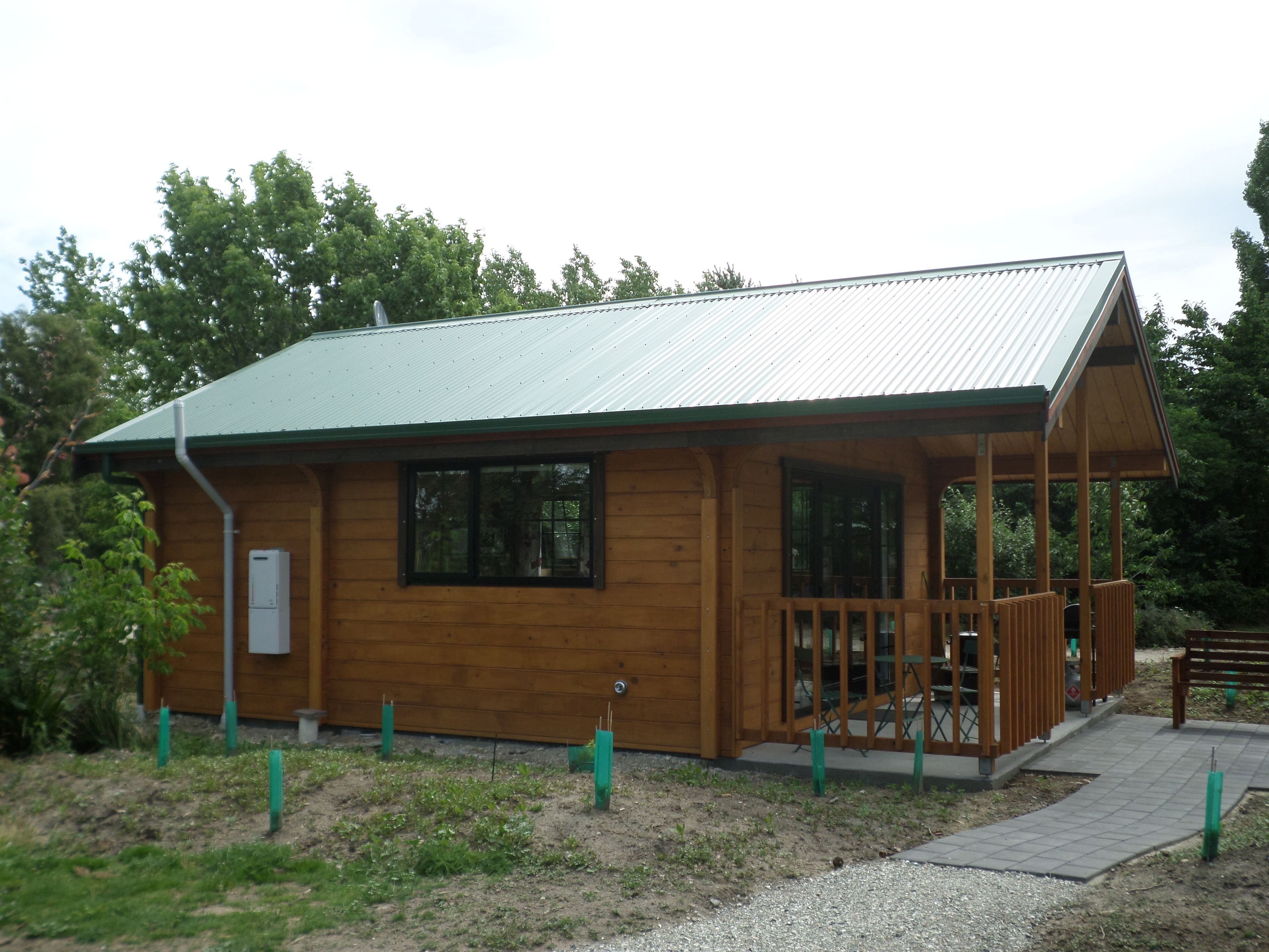 A wooden cabin with a metal roof, a porch, and a small deck.