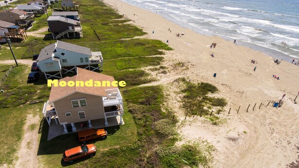 Een pand aan het strand met een groot huis, een zandstrand en de oceaan.
